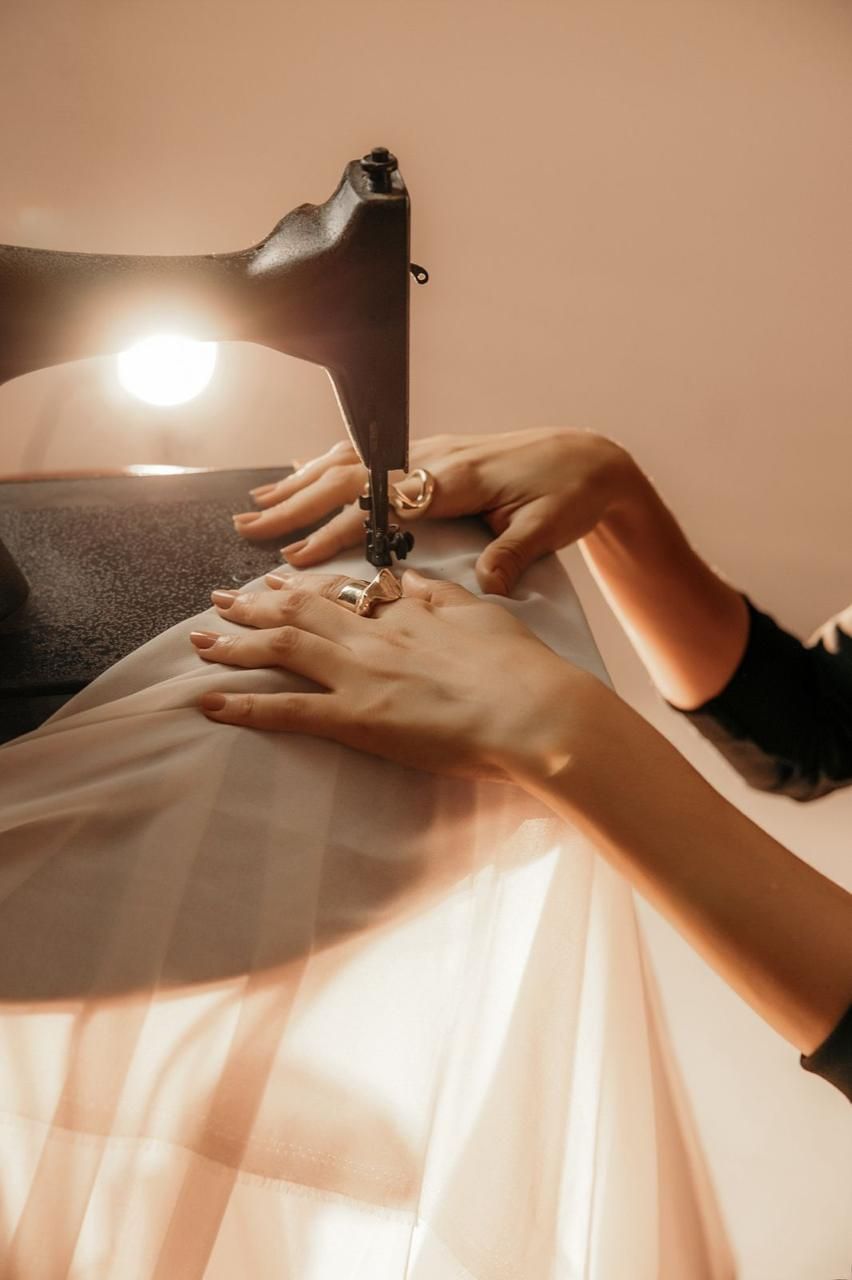 Mãos costurando vestido na máquina de costura